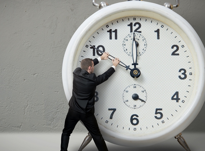 Businessman pulling a clock hand backwards